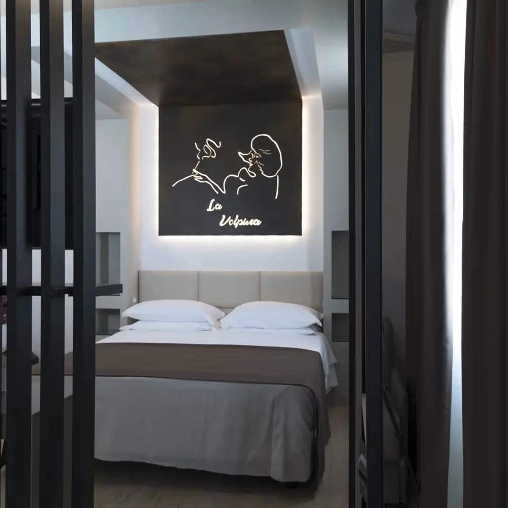 Camera da letto moderna con letto matrimoniale e quadro artistico minimalista sopra la testiera.