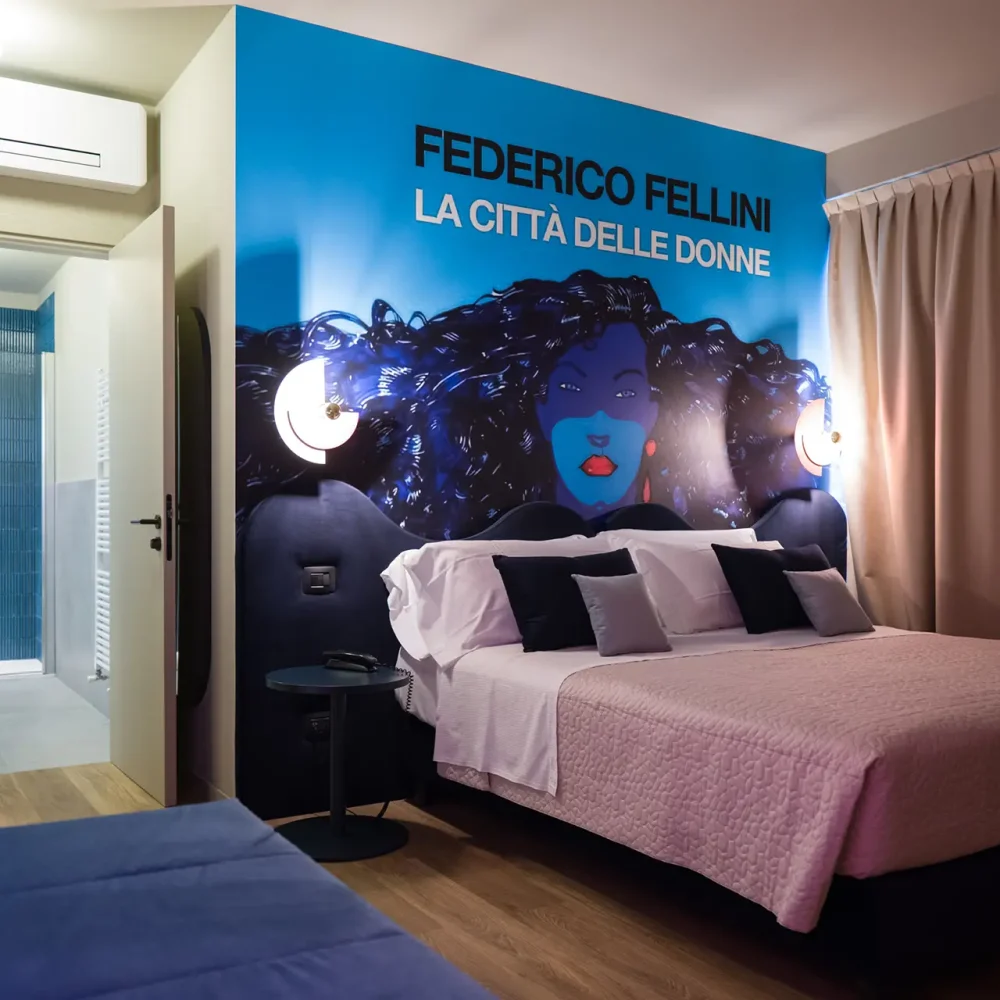 Camera d'albergo con una parete decorata ispirata a Federico Fellini, "La città delle donne".
