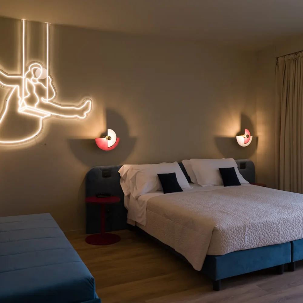 Camera da letto moderna con decorazione luminosa a parete e ampio letto matrimoniale.