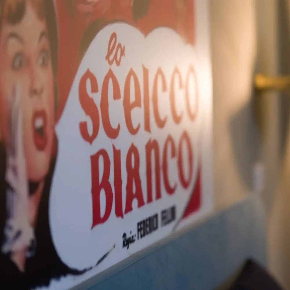 Poster sfocato del film "Lo sceicco bianco" su una parete.