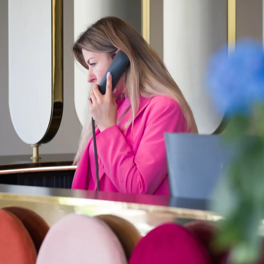 Donna al telefono in un ufficio moderno con pannelli colorati in primo piano.