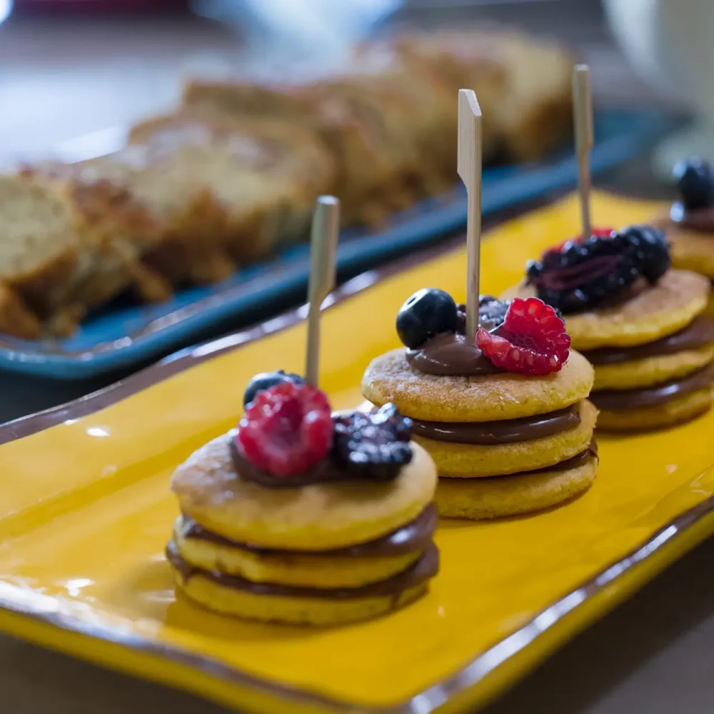 Dolcetti con biscotti e frutti di bosco su un piatto giallo.