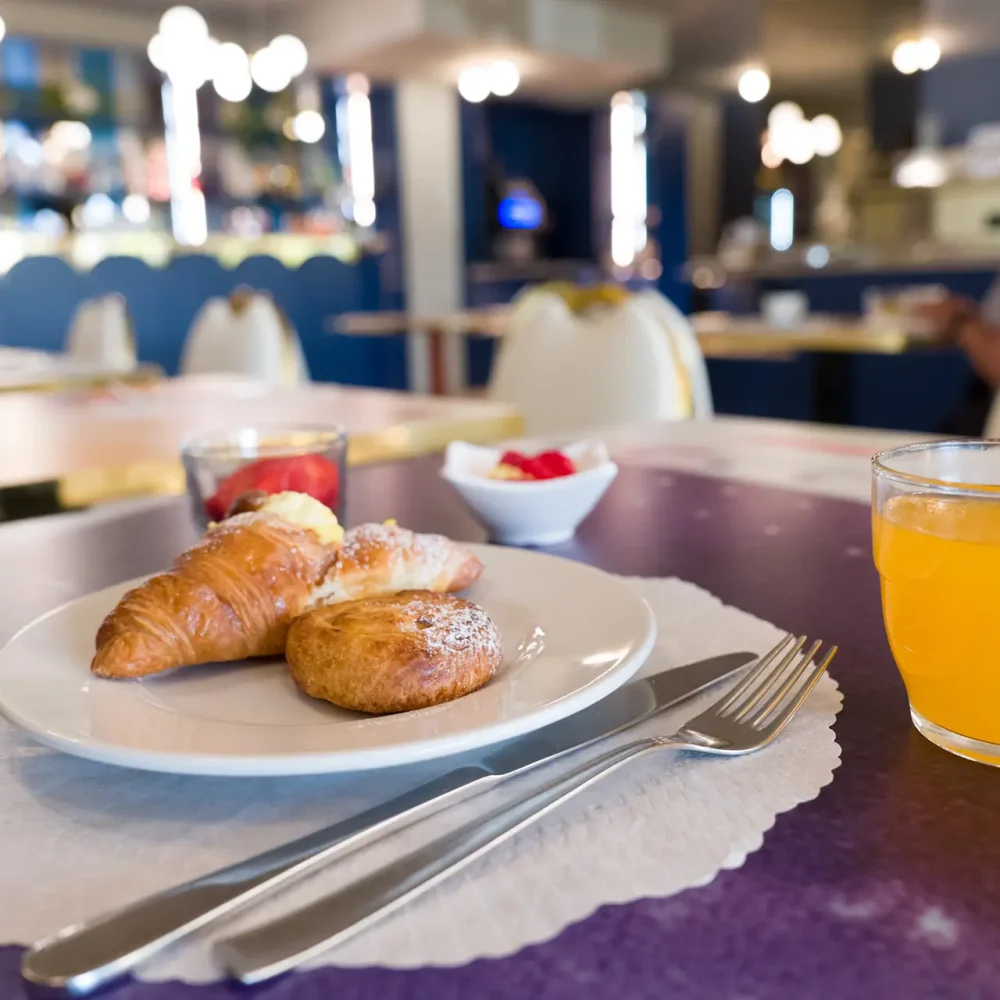 Colazione con cornetti e succo d'arancia in un bar elegante.