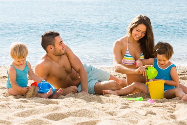 Famiglia che gioca sulla spiaggia in una giornata di sole.