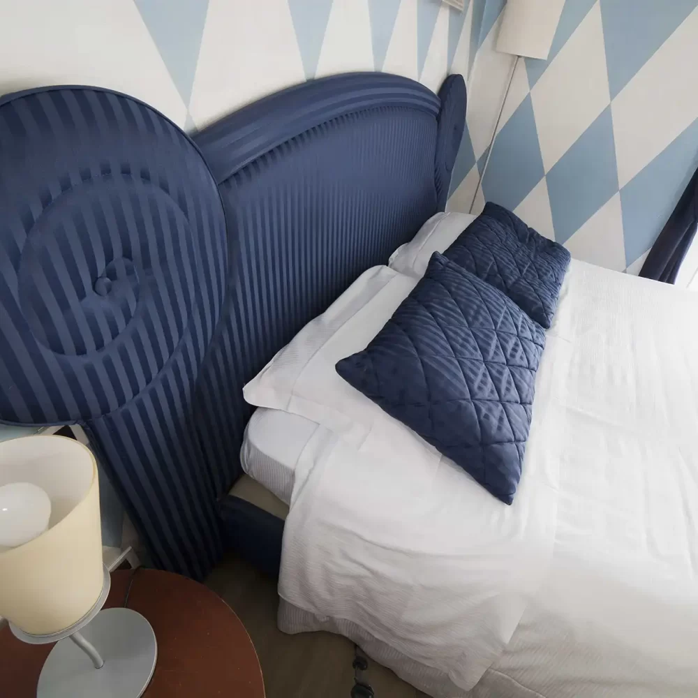 Camera da letto con letto matrimoniale e testiera blu decorata.