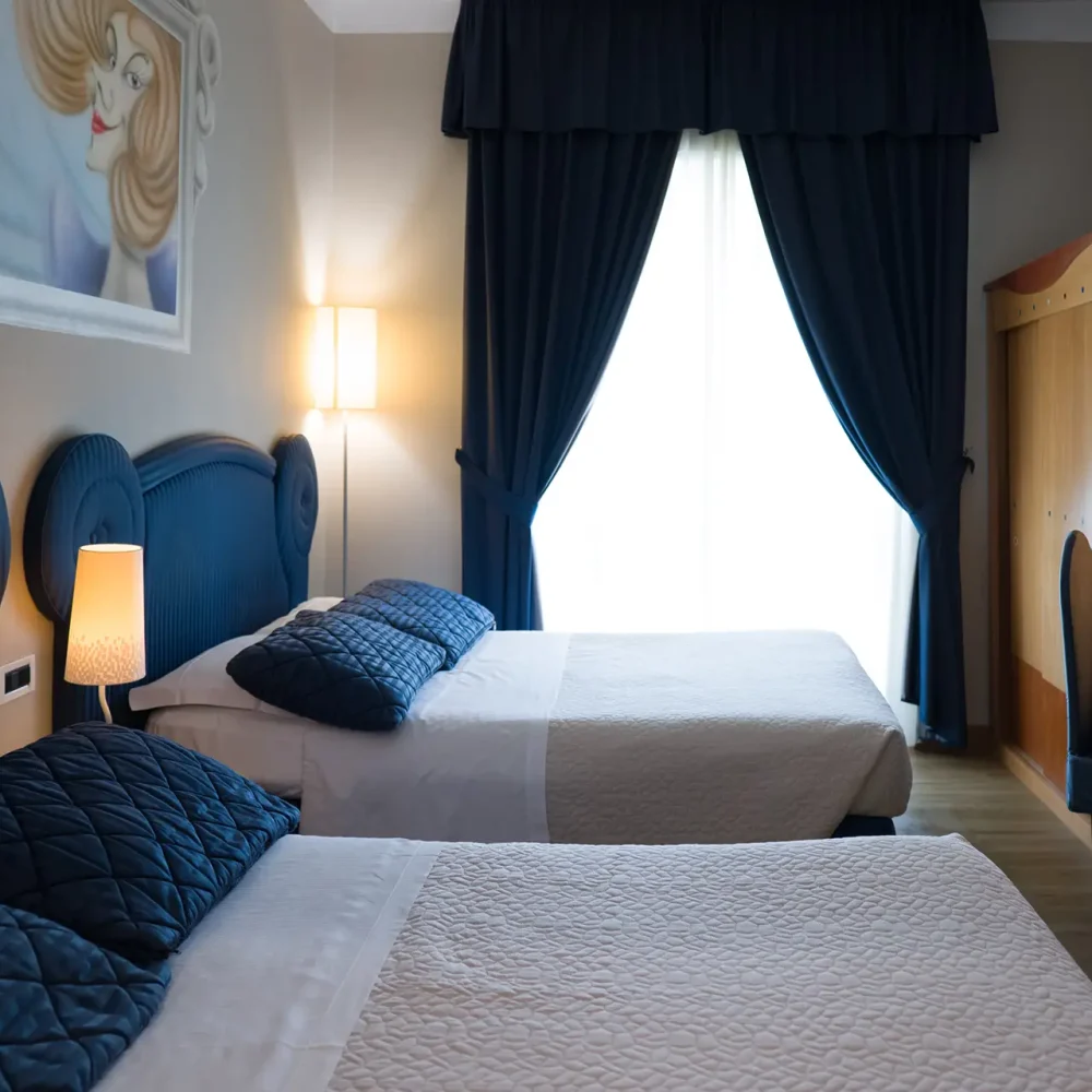 Camera d'albergo elegante con due letti, decorazioni blu e una finestra con tende.