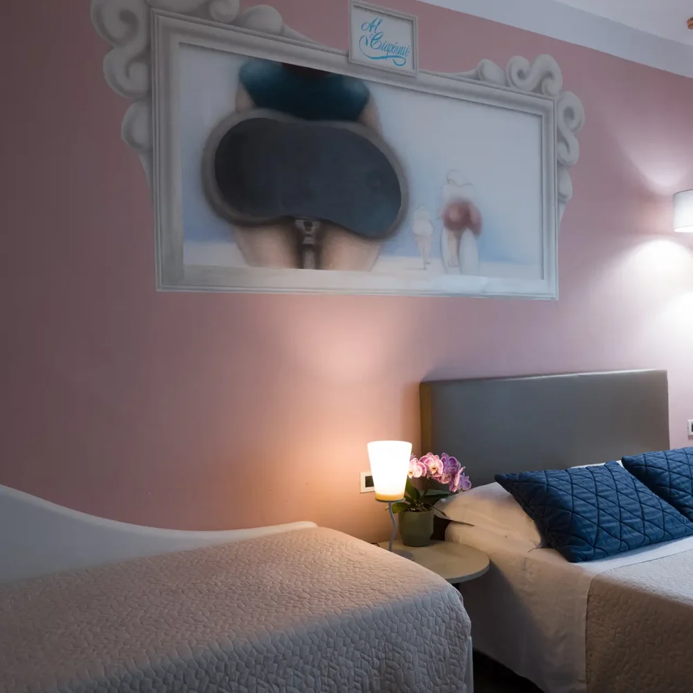 Camera da letto con pareti rosa, due letti e un dipinto sopra la testiera.