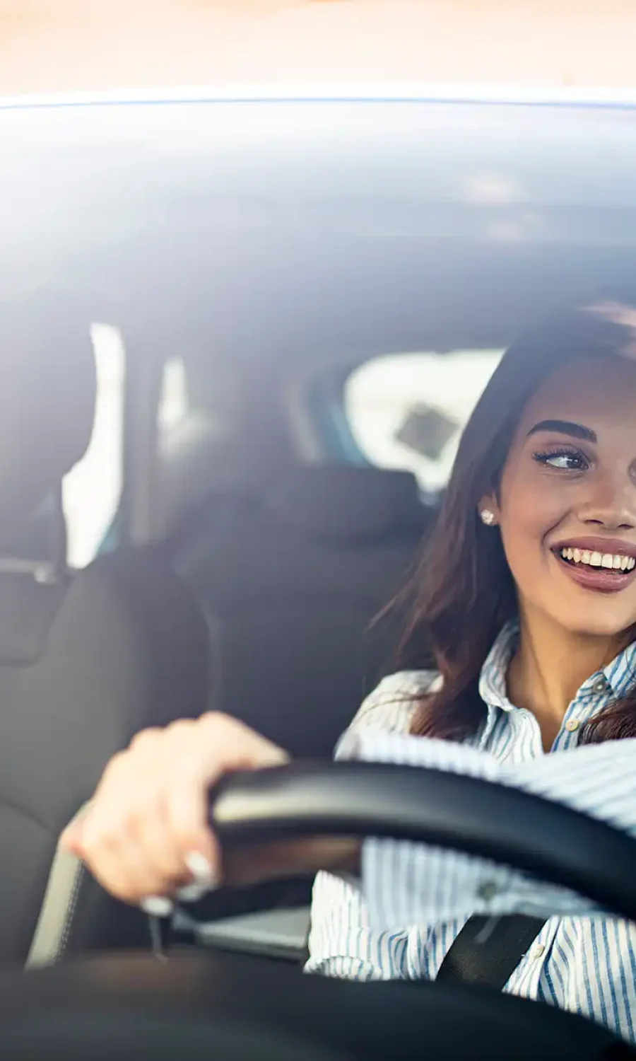 Donna sorridente alla guida di un'auto.