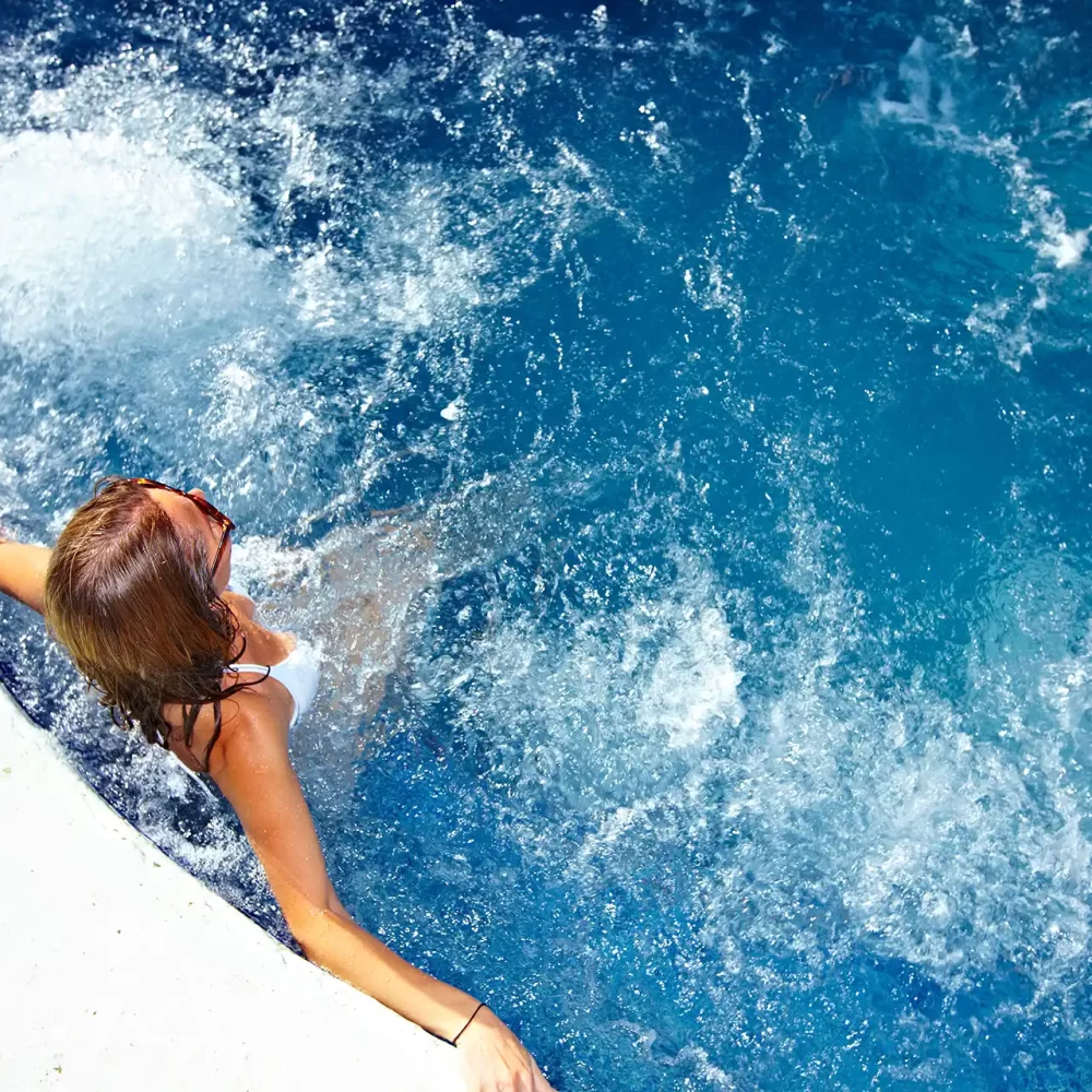 Donna che si rilassa in piscina con acqua blu vorticosa.
