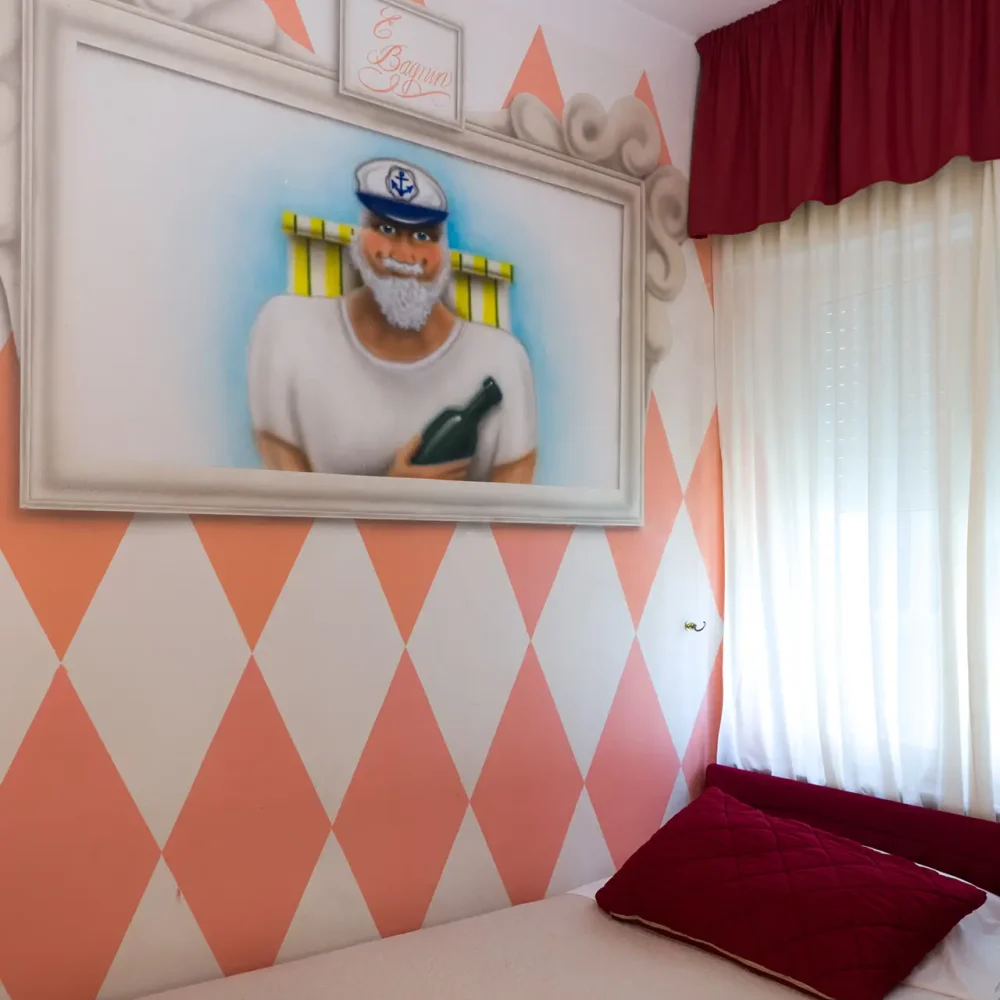 Camera con pareti a rombi rosa e bianchi, decorata con un quadro raffigurante un marinaio.